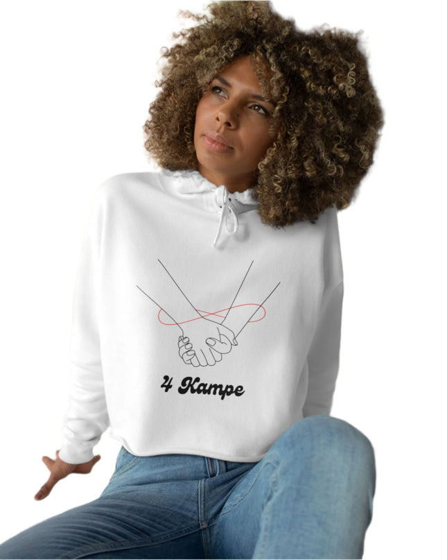 A woman sitting with a casual crop hoodie featuring a minimalist design of two hands and the text '4 KAMPE' on the front.