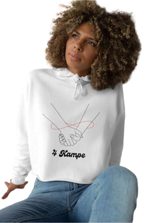 A woman sitting with a casual crop hoodie featuring a minimalist design of two hands and the text '4 KAMPE' on the front.